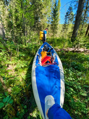 A person is standing next to a striking blue and white kayak that is nestled in a beautiful wooded...