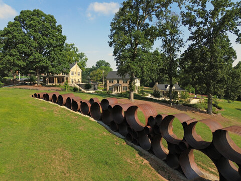 Raleigh, NC - USA - 7-8-2025:  The Attun sculpture by artist DeWitt Godfrey with the historic stone houses in the distance at Dix Park in downtown Raleigh