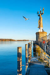 Wintry lake view with Imperia, calm water and seagull in the sky in Konstanz, Bodensee