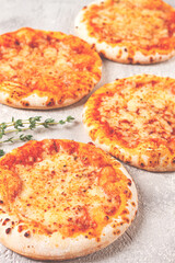 Four pizzetta Margaritas, on a light grey surface, top view,