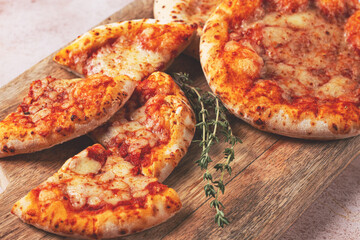 Four pizzetta Margaritas, on a cutting board, on a light gray surface, top view,
