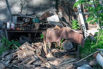 An old workshop, filled with tools, wood, and overgrown greenery.
