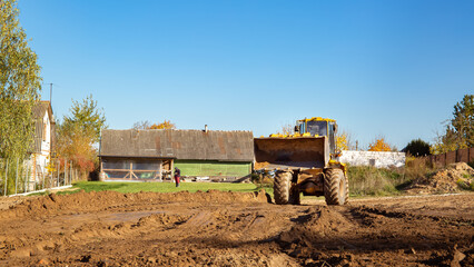 Yellow bulldozer at a construction site. Big wheel excavator leveling and clearing the land plot...