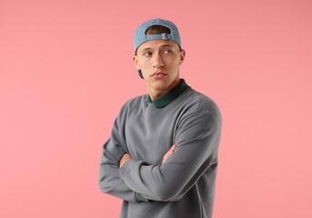 Young man in stylish baseball hat on pink background