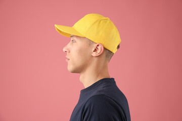 Young man in stylish baseball hat on pink background