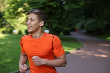 Sporty man running in park, space for text