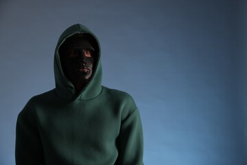 Anonymity. Man wearing mask on blue background, space for text