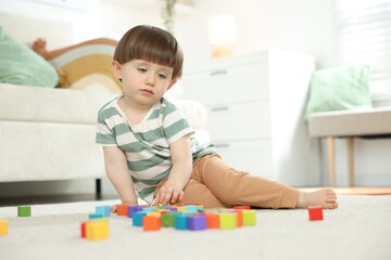 Cute little child playing with colorful cubes at home. Space for text