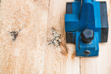 A hand-held electric planer in the hands of a craftsman. A man planing boards with an electric...