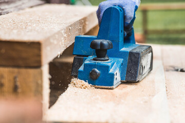 A hand-held electric planer in the hands of a craftsman. A man planing boards with an electric...