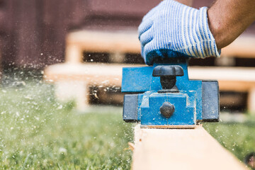 A hand-held electric planer in the hands of a craftsman. A man planing boards with an electric...