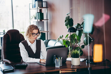 Professional businesswoman working on a laptop in a modern office setting surrounded by stylish...