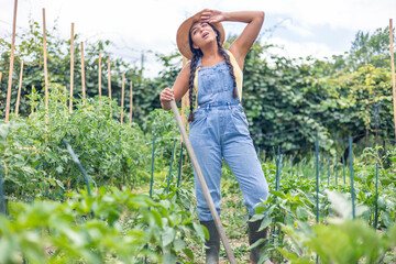 Latin farmer woman wiping sweat from forehead while working in vegetable garden