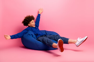 Smiling child in blue casual wear enjoying playful moment in pink background setting for lifestyle...