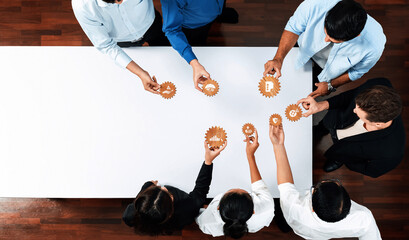 A diverse team engages in a collaborative meeting, sharing ideas represented by gear icons on a...