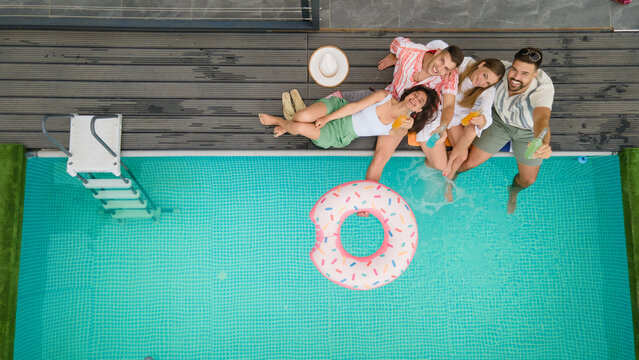 A lively scene of friends enjoying drinks and laughter at the poolside, showcasing the essence of summer joy and togetherness.Aerial view