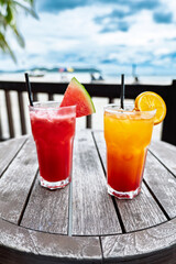 Two cocktails on a wooden table at seashore. Concept of luxury vacation. Colorfull mocktails at ocean beach bar