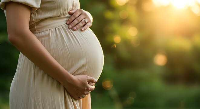 Pregnant woman cradling her belly in a sunlit outdoor setting