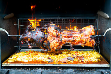 Whole pig spit roasted. Pig roasted on a barbecue spit. Outdoor Barbecue grill in open bbq pit. The little pig is roasted whole on an open fire. Outdoor piglet grilling. Pork meat garden barbecue. 