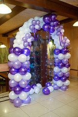 A photo backdrop made of blue and white balloons and a curtain made of small light fixtures
