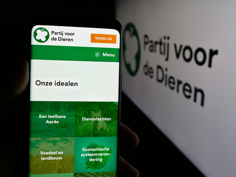 Stuttgart, Germany - 07-09-2025: Person holding smartphone with web page of Dutch party Partij voor de Dieren (PvdD) on screen in front of logo. Focus on center of phone display.