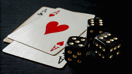 Close-up of playing cards and dice on a black surface, representing gambling, luck, and the thrill of casino games.