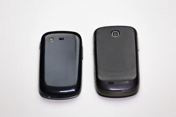 A close-up view of the rear of two vintage mobile phones, highlighting their distinct designs,...