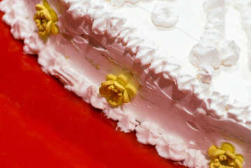 White heart shaped birthday cake. Decorated with yellow flowers and white whipped cream with the inscription Happy Birthday