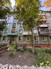 Old Soviet Apartment Building with Green Facade and Garden