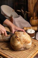 Healthy, organic, whole and sliced ​​homemade sourdough bread with ham and cheese on a wooden table and kitchen utensils with an airy crumb and crispy crust. 