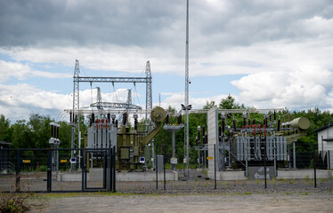 Electric power substation with transformers and high-voltage equipment outdoors on cloudy day
