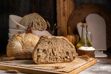 Healthy, organic, whole and sliced ​​homemade sourdough bread with ham and cheese on a wooden table and kitchen utensils with an airy crumb and crispy crust. 