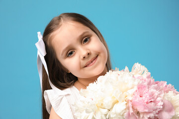 Cute little girl with bouquet of beautiful peonies on light blue background