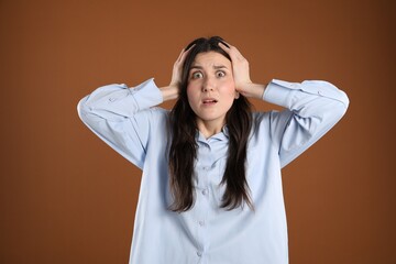 Portrait of shocked woman on brown background