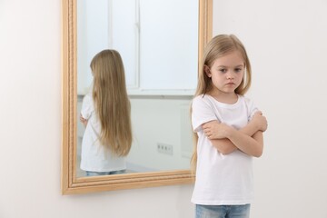 Upset little girl near mirror at home