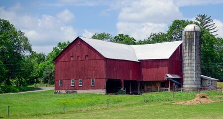Obraz premium Rustic red barn and silo in a green field.
