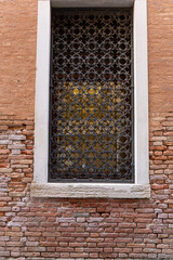 A detailed close-up of a Venetian window with ornate wrought iron, flower pots, and weathered stone and brickwork.