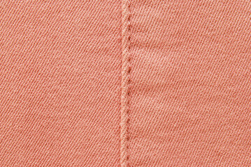 Fototapeta premium Pink cotton twill texture, a detail of seamed pink pants with a stitch in the center 