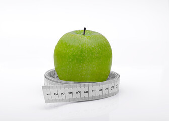 Green apple with a measuring tape on a white background. Healthy eating, dieting, and weight...