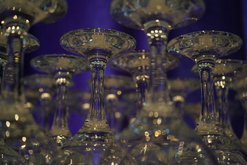 Upside-down wine glasses with intricate stems and transparent bowls are arranged closely together....