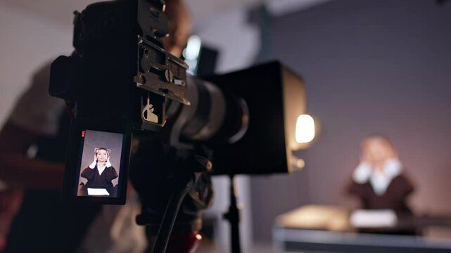 Brunette Caucasian lady on the display of modern camera. Close up. Unrecognized woman stands near the camera fixing equipment. Blurred backdrop.