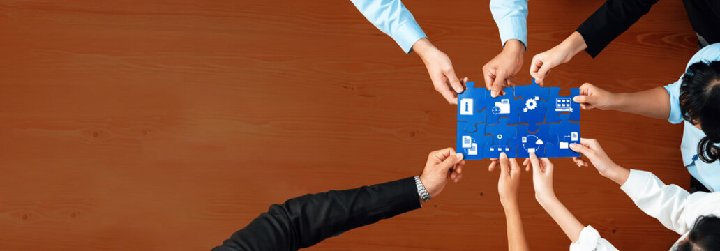 A diverse business team gathers around a blue puzzle piece filled with icons, symbolizing their collaborative efforts in management and strategic planning. Amity - Powered by Adobe