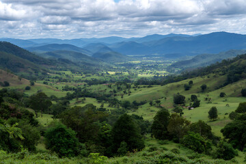 Lush Green Rolling Hills Valley Landscape Scenic View Distant Blue Mountains Cloudy Sky Rural Farmland