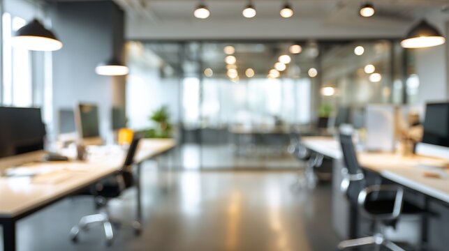 Modern office workspace with blurred background showcasing desks, chairs, and lighting fixtures in a collaborative environment.