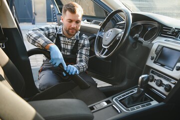 Car detailing and car care concept - Professional using steam vacuum for draining stains