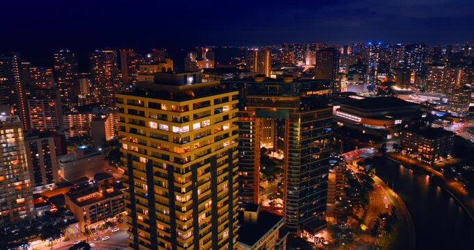 Dazzling high-rises of the vibrant city. Drone footage at the tops of the buildings at night. Honolulu, Hawaii, USA.