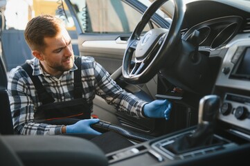 Car detailing and car care concept - Professional using steam vacuum for draining stains