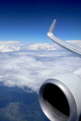 Airplane Wing and Engine View Above the Clouds From a Window Seat. Passenger view of airplane wing...