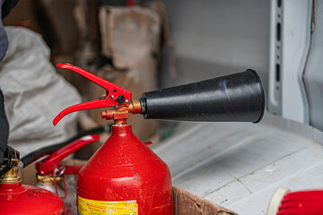 Close-up of two red fire extinguishers in an industrial setting, one partially inserted into the...