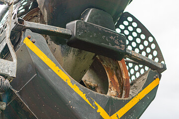 Close-up view of rusted, worn concrete mixer truck gear and pulley system with yellow warning...